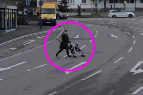 Mutter mit Kinderwagen rennt über die mehrspurige Straße